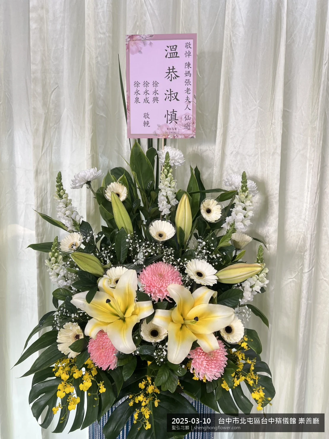台中北屯台中殯儀館 崇善廳前置高架白菊花籃，氛圍安寧整齊。挑高花架穩固、字牌方向清晰，於春暖氣候濕潤就位完成，陪伴家屬度過難捨時刻，聖弘花藝在地團隊現場實拍照。