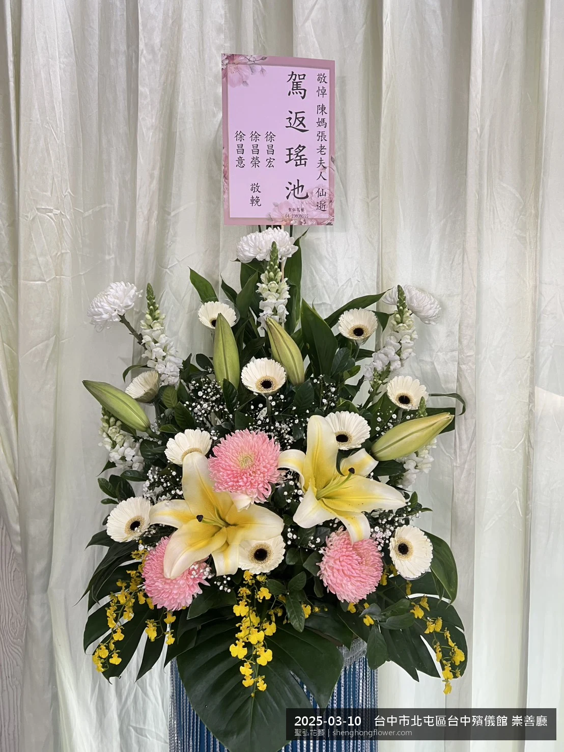 春暖氣候濕潤下高架白菊花籃並陳，雙層花籃結構、上層紅玫瑰下層白菊，送達台中北屯台中殯儀館 崇善廳前後整體沉靜典雅，傳達家屬最後敬意，聖弘花藝在地團隊現場實拍照。