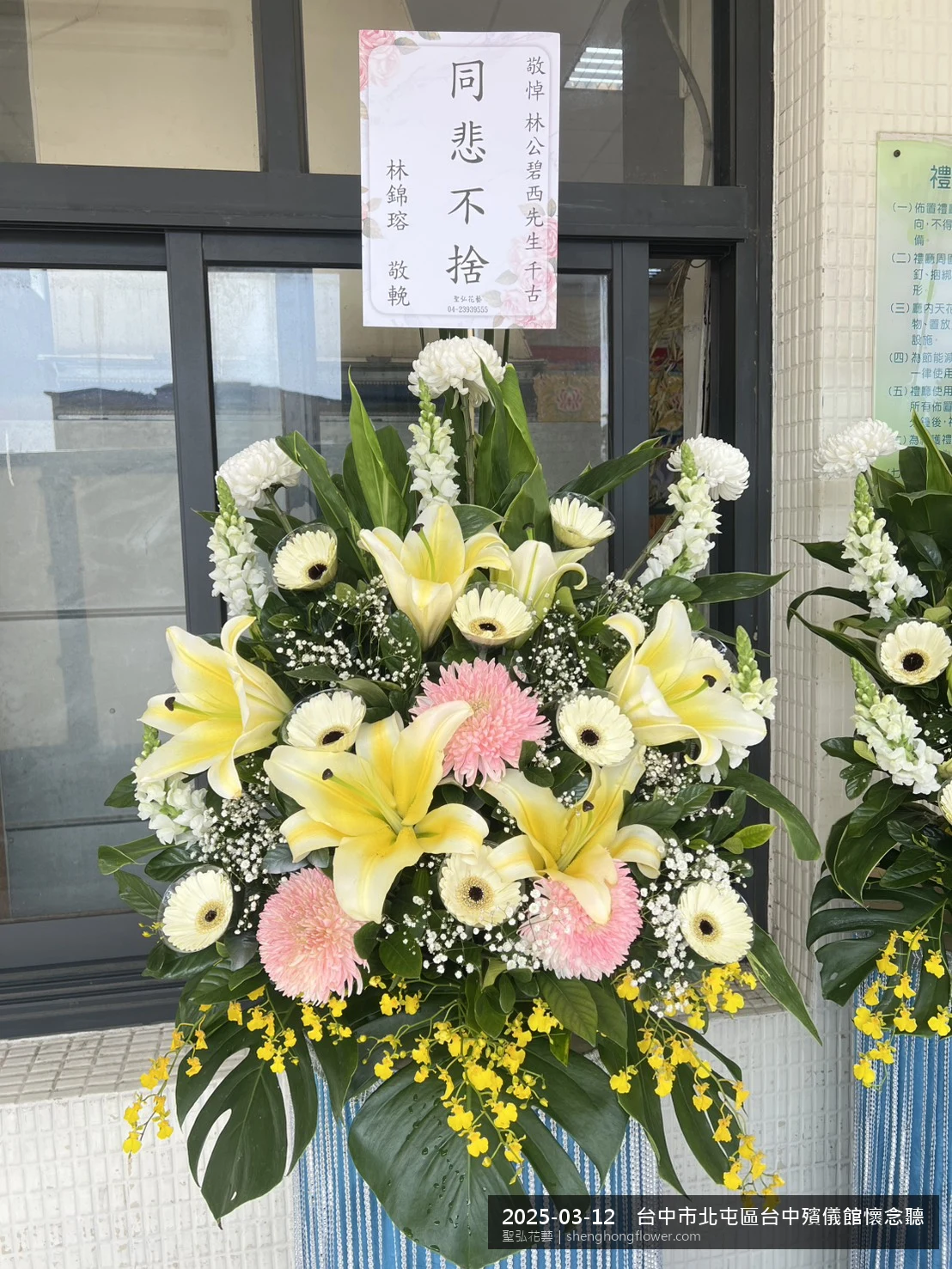 高架白菊花籃主花百合配劍蘭、底部黃菊填充，於春暖氣候濕潤花朵保鮮極佳。送達台中北屯台中殯儀館懷念聽前後完成擺設，寧靜哀思，寄託家屬哀思敬意，聖弘花藝在地團隊現場實拍照。