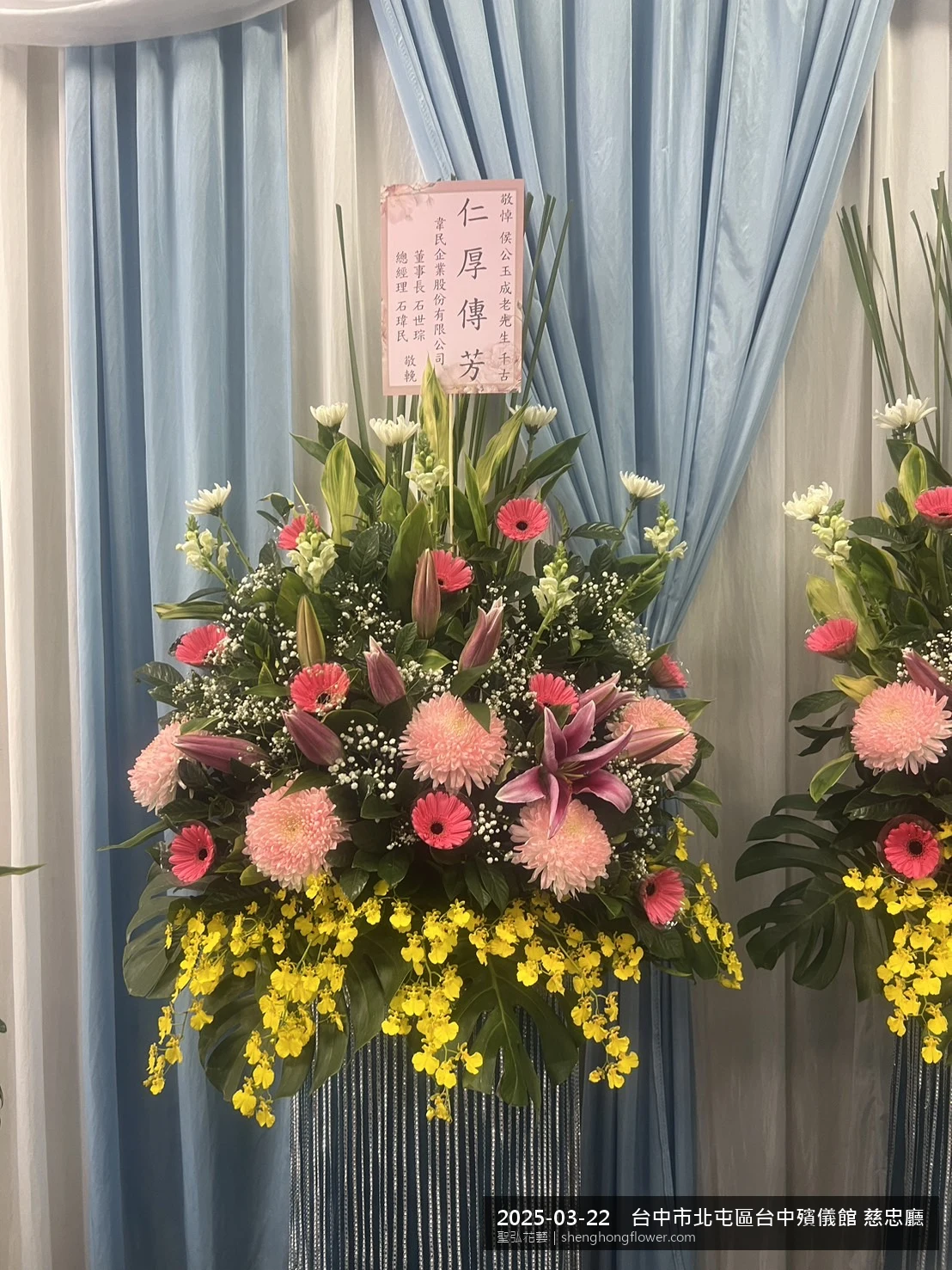 春暖氣候濕潤下高架白菊花籃並陳，雙層花籃結構、上層紅玫瑰下層白菊，送達台中北屯台中殯儀館 慈忠廳前後整體安寧整齊，傳達家屬最後敬意，聖弘花藝在地團隊現場實拍照。