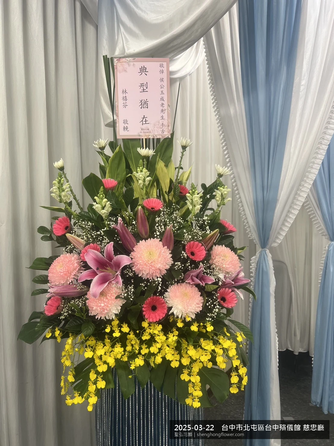 高架白菊花籃主花百合配劍蘭、底部黃菊填充，於春暖氣候濕潤花朵保鮮極佳。送達台中北屯台中殯儀館 慈忠廳前後完成擺設，沉靜典雅，寄託家屬哀思敬意，聖弘花藝在地團隊現場實拍照。