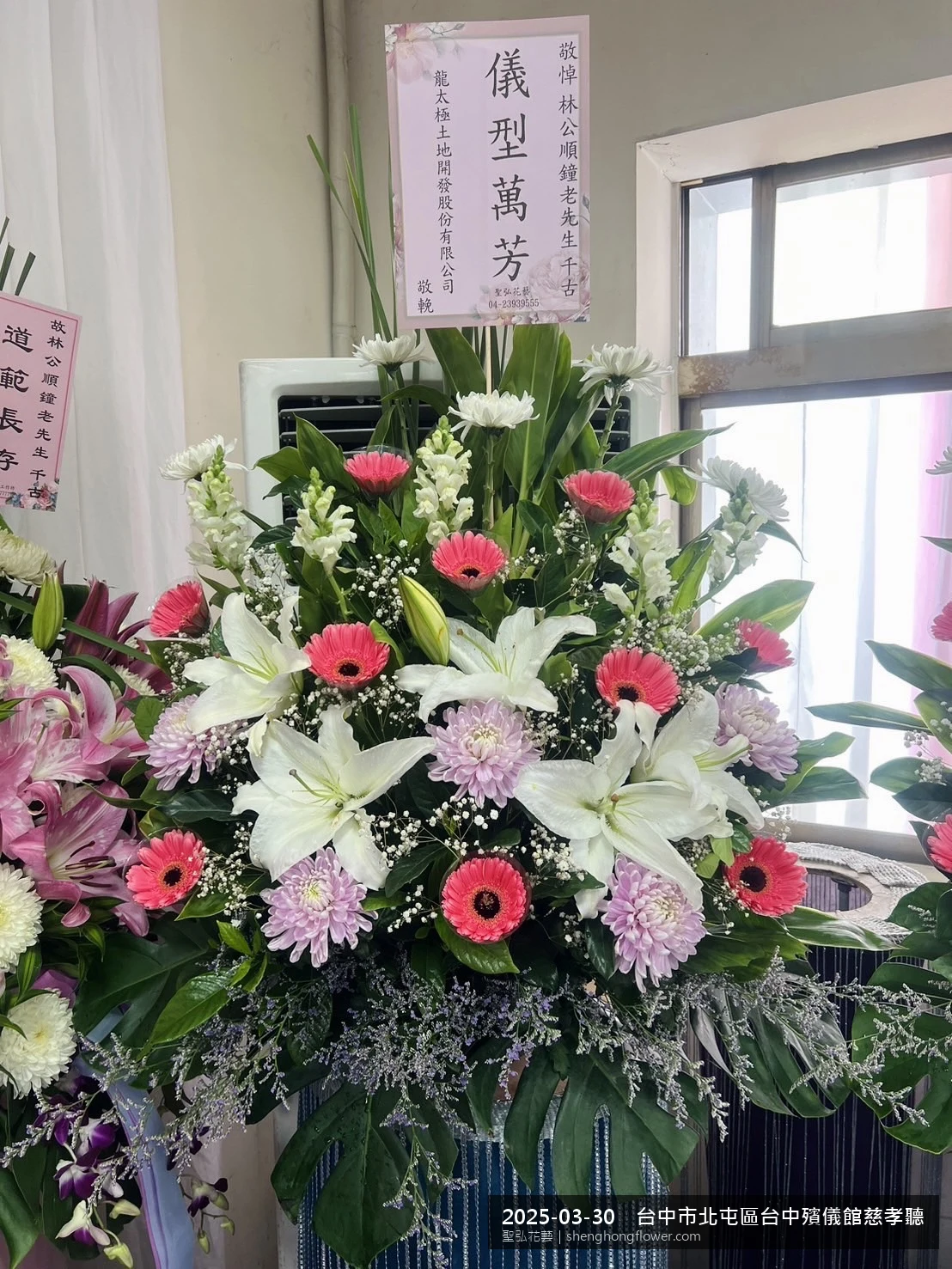 台中北屯台中殯儀館慈孝聽前氣氛沉靜典雅，選用高架白菊花籃並高架支架對稱、白菊圍裙裝飾，搭配春暖氣候濕潤的場景，撫慰家屬不捨之情，聖弘花藝在地團隊現場實拍照提供在地專業配送服務。