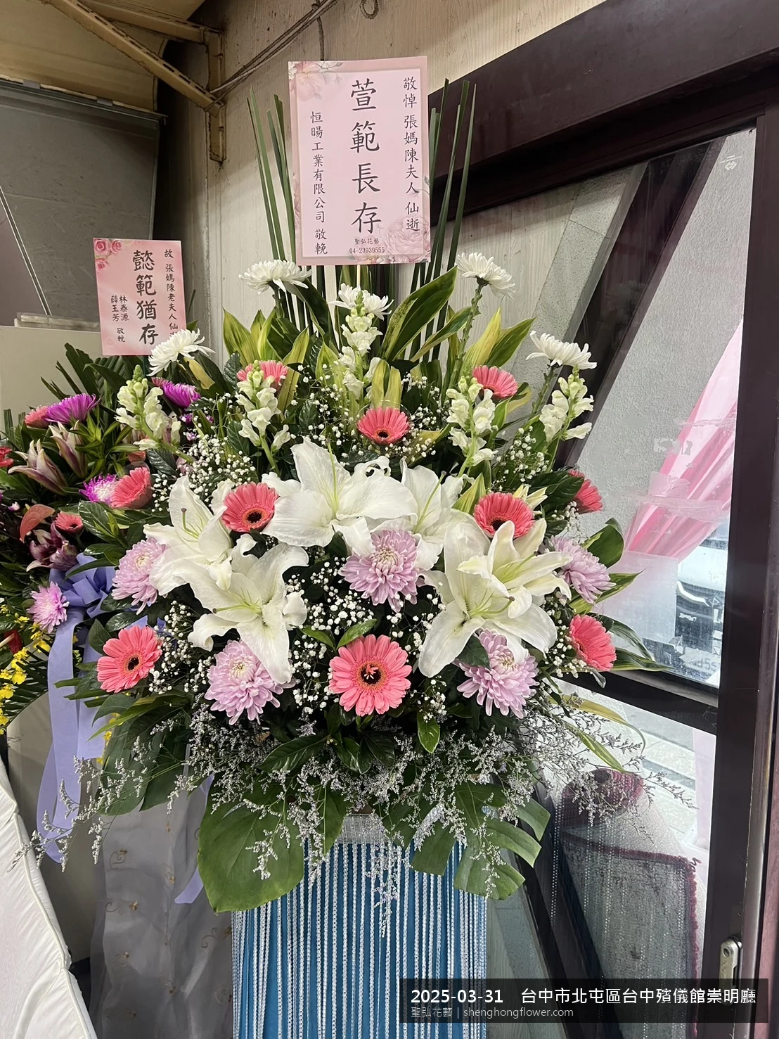 春暖氣候濕潤下，台中北屯台中殯儀館崇明廳前光線柔和。我們選用高架白菊花籃，雙劍蘭挑高、黃菊鋪底，現場顯得寧靜哀思，誠摯傳達對家屬的關懷，聖弘花藝在地團隊現場實拍照。