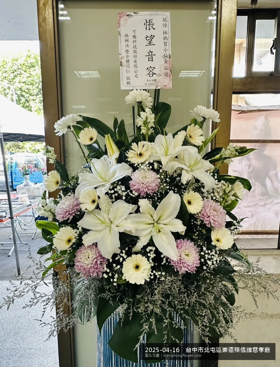 台中北屯崇德殯儀館慈孝廳前置高架白菊花籃，氛圍寧靜哀思。挑高花架穩固、字牌方向清晰，於春末穀雨時節氣候溫暖偏濕就位完成，陪伴家屬度過難捨時刻，聖弘花藝在地團隊現場實拍照。