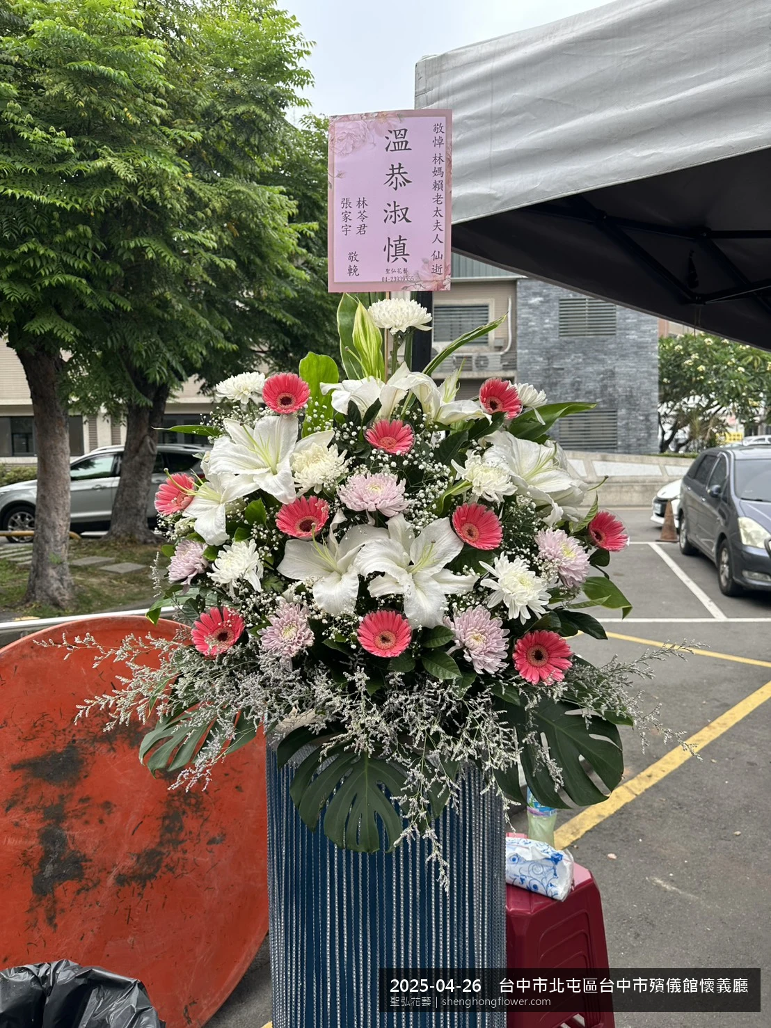 高架白菊花籃主花百合配劍蘭、底部黃菊填充，於春末穀雨時節氣候溫暖偏濕花朵保鮮極佳。送達台中北屯台中市殯儀館懷義廳前後完成擺設，莊嚴端莊，寄託家屬哀思敬意，聖弘花藝在地團隊現場實拍照。
