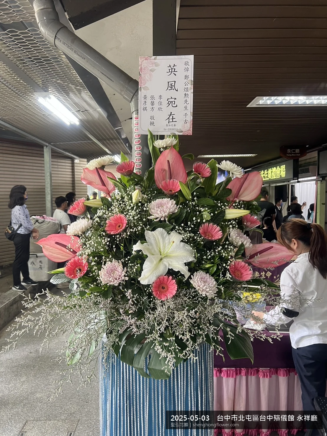 台中北屯台中殯儀館 永祥廳前氣氛莊嚴端莊，選用高架白菊花籃並高架支架對稱、白菊圍裙裝飾，搭配初夏暖陽氣候宜人的場景，撫慰家屬不捨之情，聖弘花藝在地團隊現場實拍照。