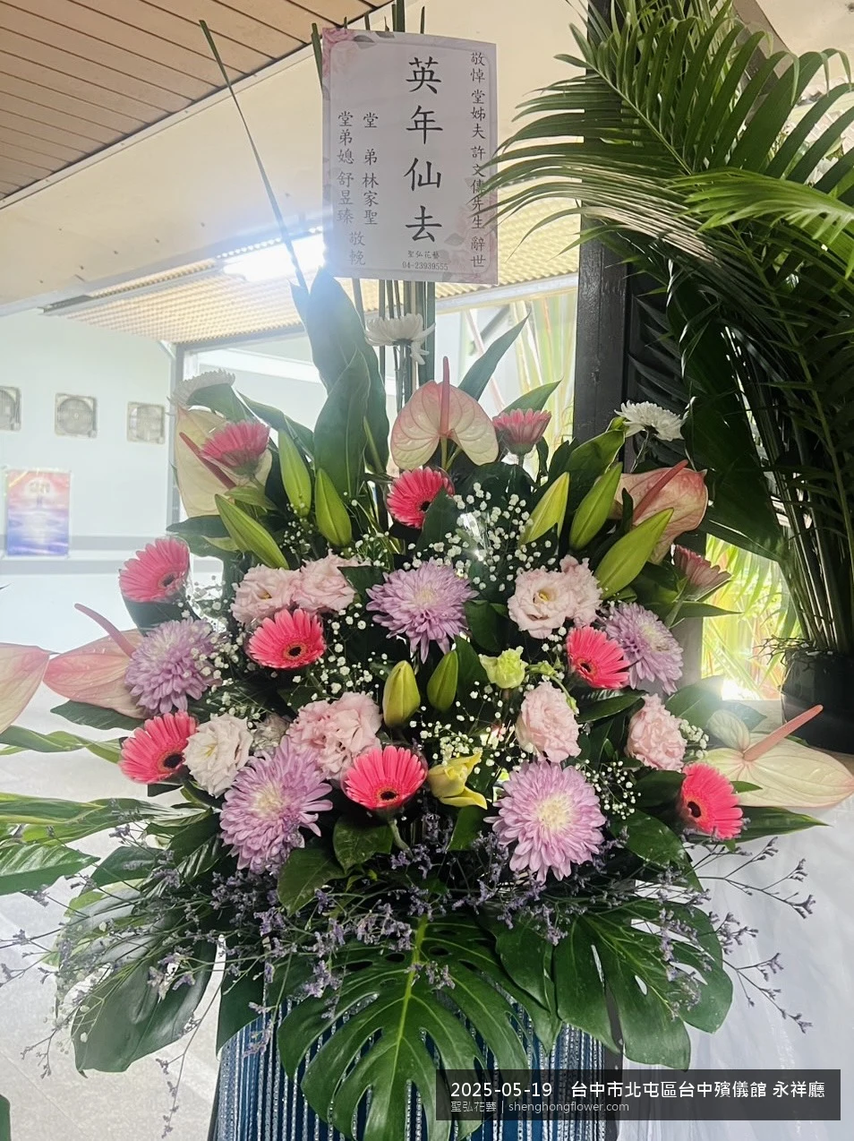 台中北屯台中殯儀館 永祥廳前置高架白菊花籃，氛圍莊嚴端莊。挑高花架穩固、字牌方向清晰，於初夏暖陽氣候宜人就位完成，陪伴家屬度過難捨時刻，聖弘花藝在地團隊現場實拍照。