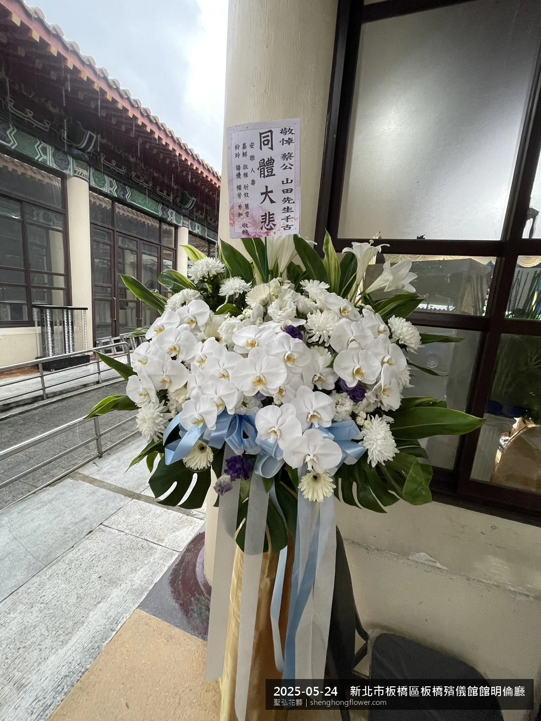 初夏暖陽氣候宜人下高架白菊花籃並陳，雙層花籃結構、上層紅玫瑰下層白菊，送達新北板橋板橋殯儀館館明倫廳前後整體陳設整齊，配合主人家完成擺設，聖弘花藝在地團隊現場實拍照。