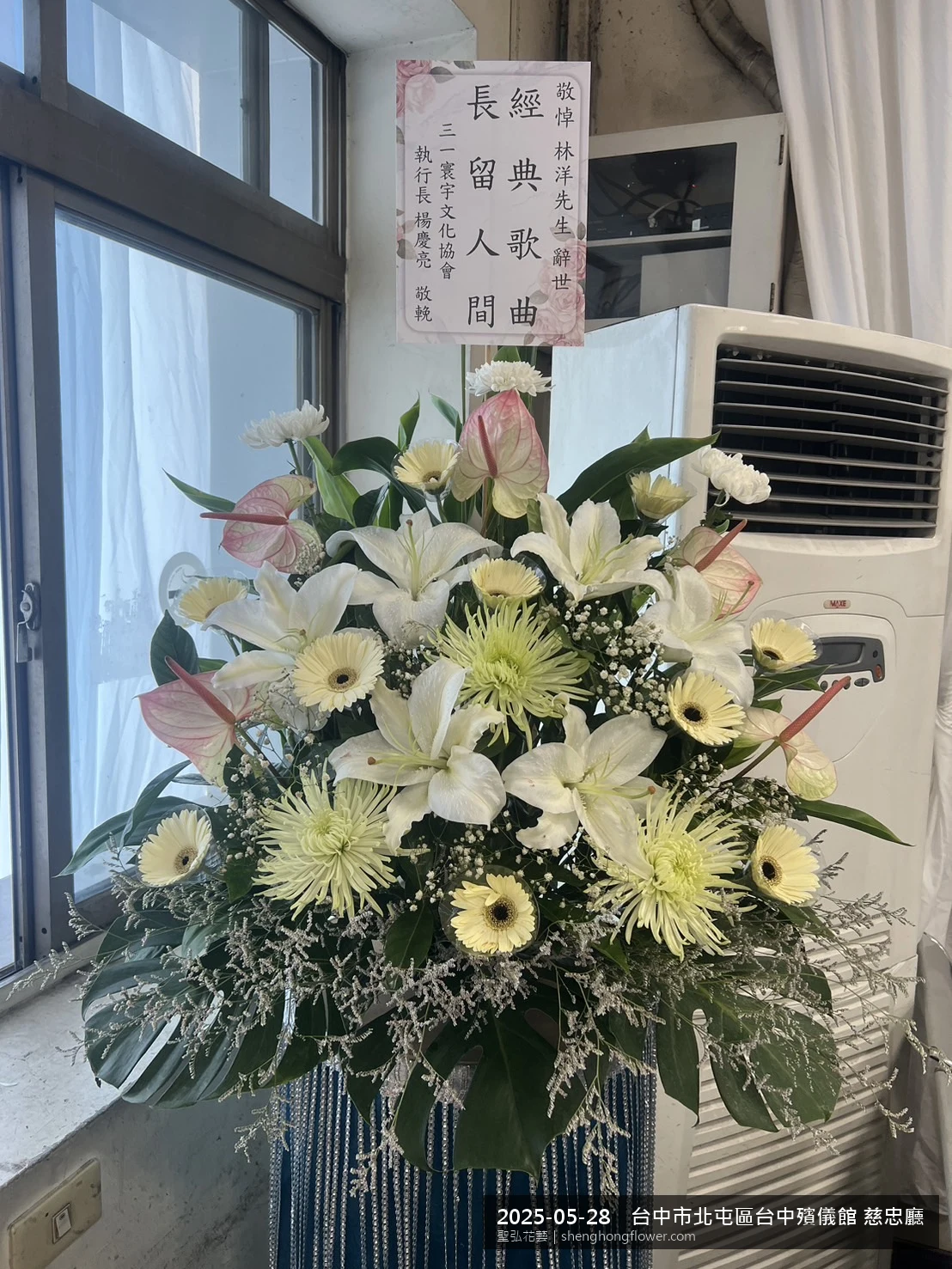 台中北屯:台中殯儀館 慈忠廳前氣氛安寧整齊，選用高架白菊花籃並高架支架對稱、白菊圍裙裝飾，搭配初夏暖陽氣候宜人的場景，撫慰家屬不捨之情，聖弘花藝在地團隊現場實拍照。
