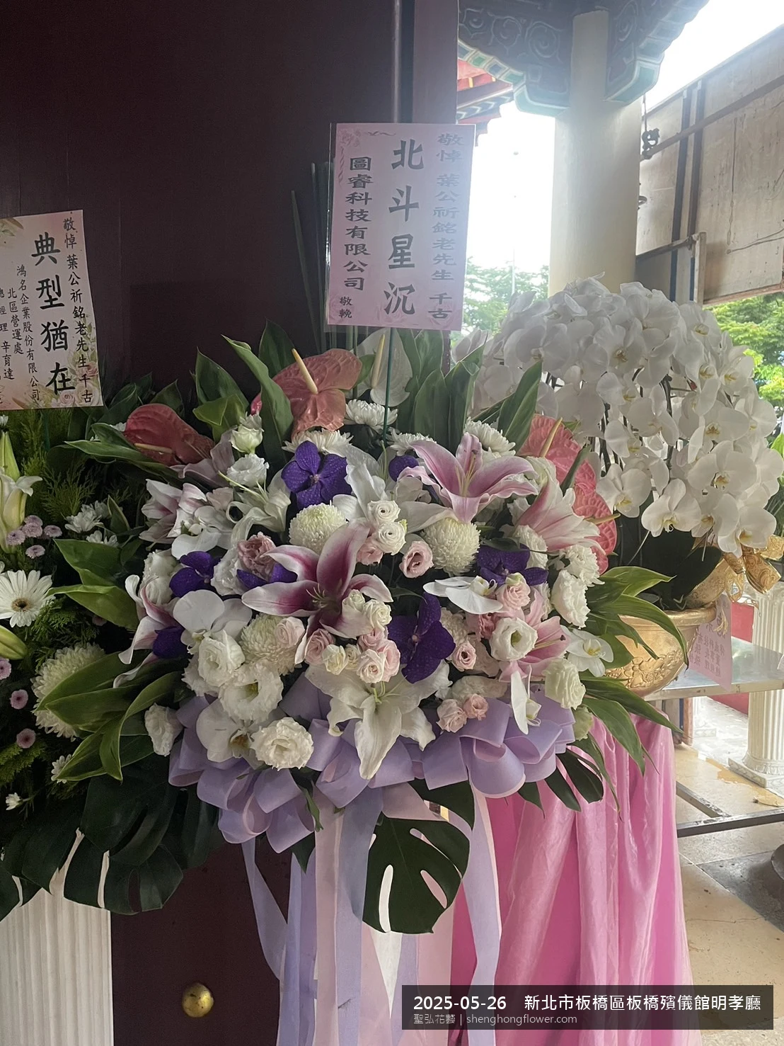 新北板橋板橋殯儀館明孝廳前氣氛配置妥當，選用高架白菊花籃並高架支架對稱、白菊圍裙裝飾，搭配初夏暖陽氣候宜人的場景，依指定方位整齊就位，聖弘花藝在地團隊現場實拍照。
