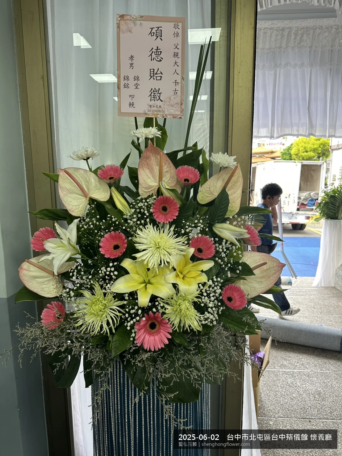 盛夏午後氣候炎熱下高架白菊花籃並陳，雙層花籃結構、上層紅玫瑰下層白菊，送達台中北屯台中殯儀館 懷義廳前後整體莊嚴端莊，傳達家屬最後敬意，聖弘花藝在地團隊現場實拍照。