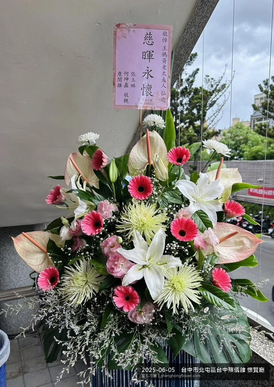 盛夏午後氣候炎熱下，台中北屯台中殯儀館 懷賢廳前光線柔和。我們選用高架白菊花籃，雙劍蘭挑高、黃菊鋪底，現場顯得安寧整齊，誠摯傳達對家屬的關懷，聖弘花藝在地團隊現場實拍照。
