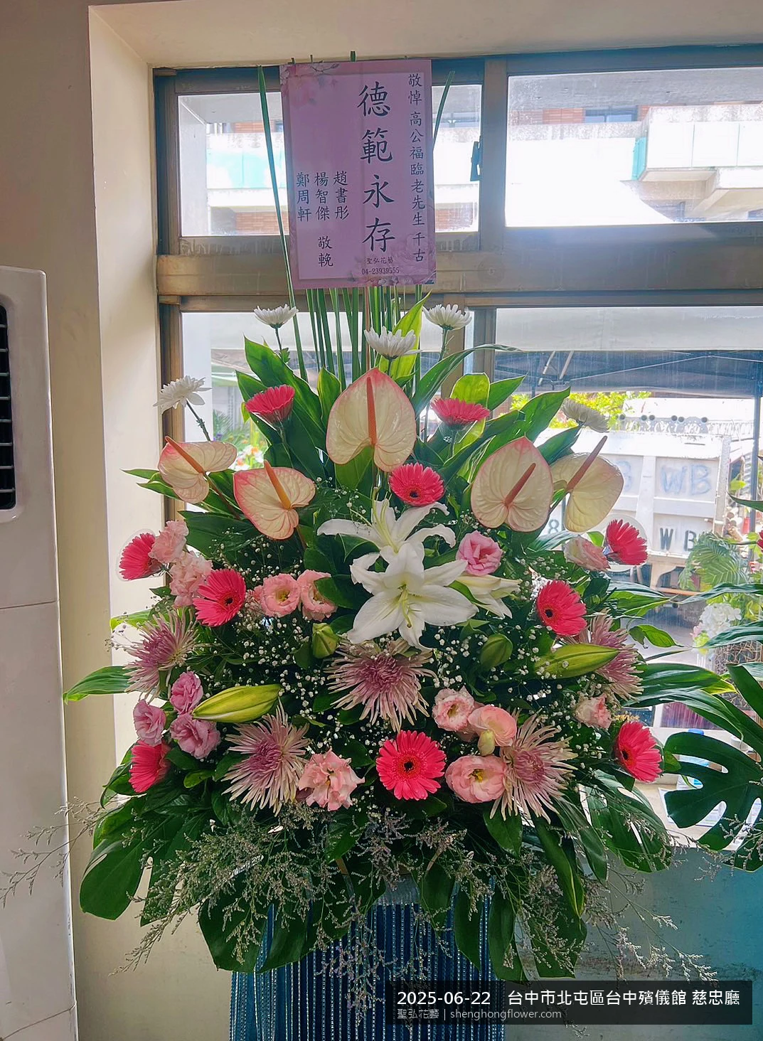 高架白菊花籃主花百合配劍蘭、底部黃菊填充，於盛夏午後氣候炎熱花朵保鮮極佳。送達台中北屯台中殯儀館 慈忠廳前後完成擺設，素雅莊重，寄託家屬哀思敬意，聖弘花藝在地團隊現場實拍照。