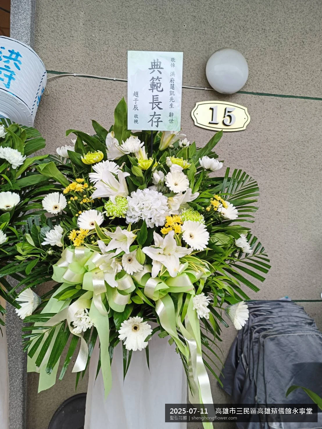 盛夏陽光氣候悶熱下，高雄三民高雄殯儀館永寧堂前光線柔和。我們選用高架白菊花籃，雙劍蘭挑高、黃菊鋪底，現場顯得配置妥當，於現場完成定位，聖弘花藝在地團隊現場實拍照。