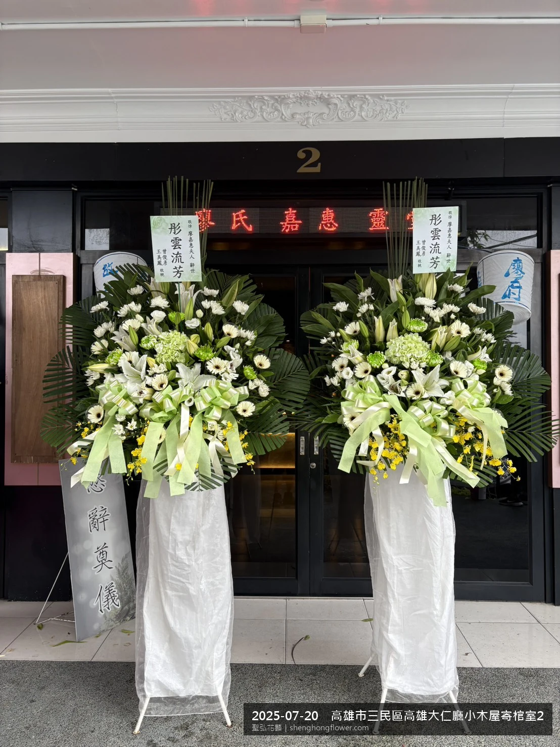 高雄三民高雄大仁廳小木屋寄棺室現場氣氛配置妥當，選用高架白菊花籃並高架支架對稱、白菊圍裙裝飾，搭配盛夏陽光氣候悶熱的場景，依指定方位整齊就位，聖弘花藝在地團隊現場實拍照。