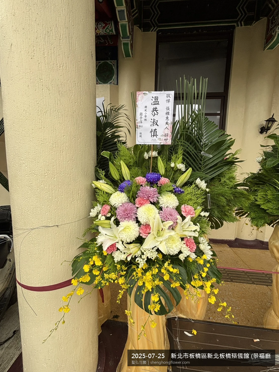 新北板橋新北板橋殯儀館 (景福廳)前置高架白菊花籃，氛圍整潔有序。挑高花架穩固、字牌方向清晰，於盛夏陽光氣候悶熱就位完成，於現場完成定位，聖弘花藝在地團隊現場實拍照。