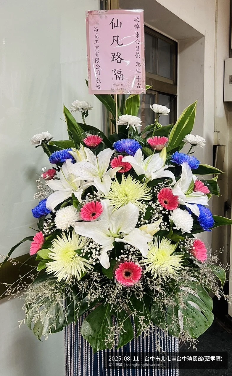 台中北屯台中殯儀館(慈孝廳)前氣氛素雅莊重，選用高架白菊花籃並高架支架對稱、白菊圍裙裝飾，搭配夏末暑熱氣候漸轉的場景，撫慰家屬不捨之情，聖弘花藝在地團隊現場實拍照。
