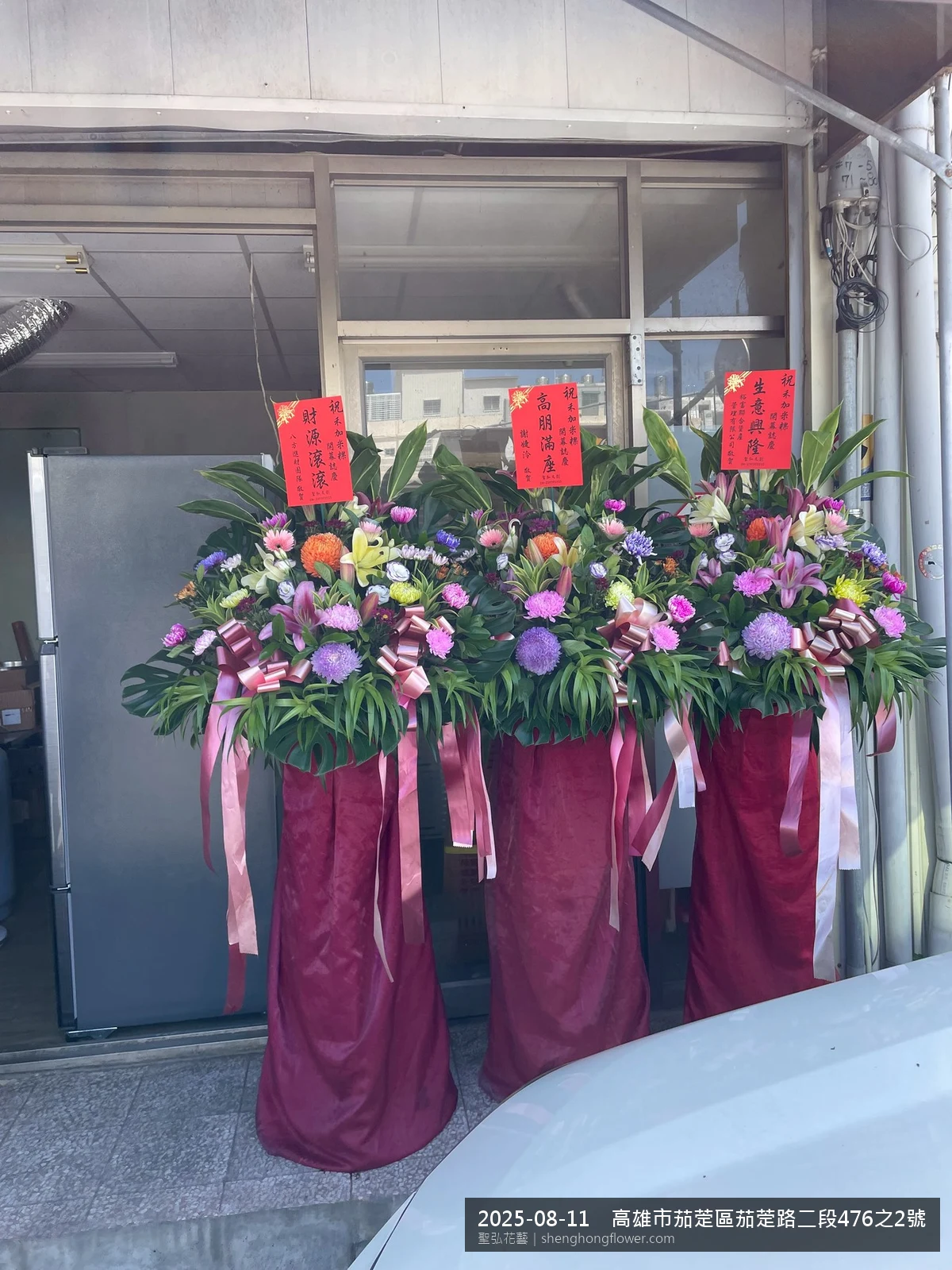 高雄茄萣茄萣路現場氣氛華貴隆重，選用高架白菊花籃並高架支架對稱、白菊圍裙裝飾，搭配夏末暑熱氣候漸轉的場景，象徵生意興隆鴻圖大展，聖弘花藝在地團隊現場實拍照提供在地專業配送服務。