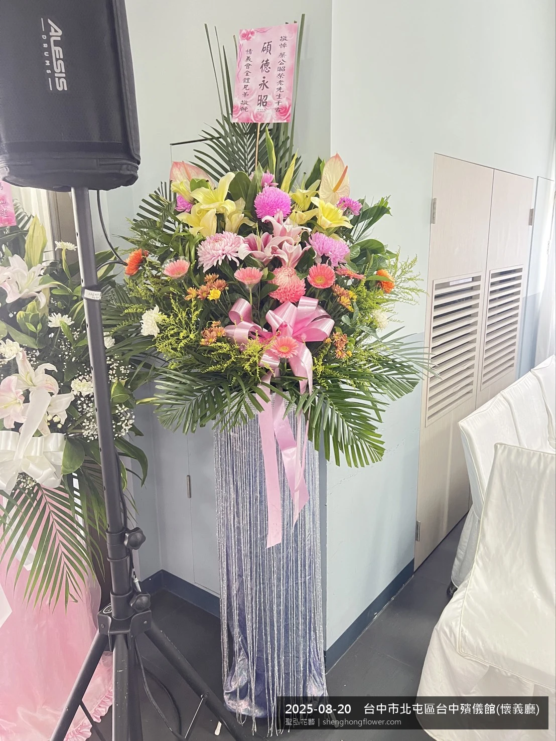 台中北屯台中殯儀館(懷義廳前置高架白菊花籃，氛圍安寧整齊。挑高花架穩固、字牌方向清晰，於夏末暑熱氣候漸轉就位完成，陪伴家屬度過難捨時刻，聖弘花藝在地團隊現場實拍照。