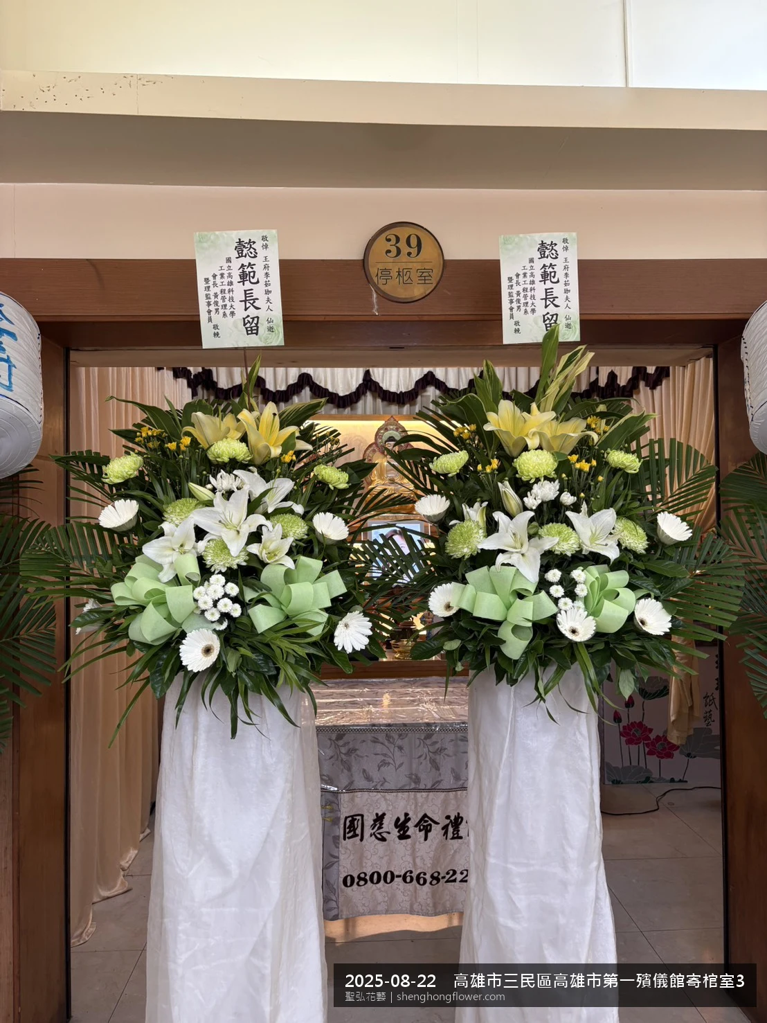 夏末暑熱氣候漸轉下白菊喪禮花籃並陳，雙花籃對稱擺放、底盤穩固，送達高雄三民高雄市第一殯儀館寄棺室前後整體整潔有序，配合主人家完成擺設，聖弘花藝在地團隊現場實拍照。