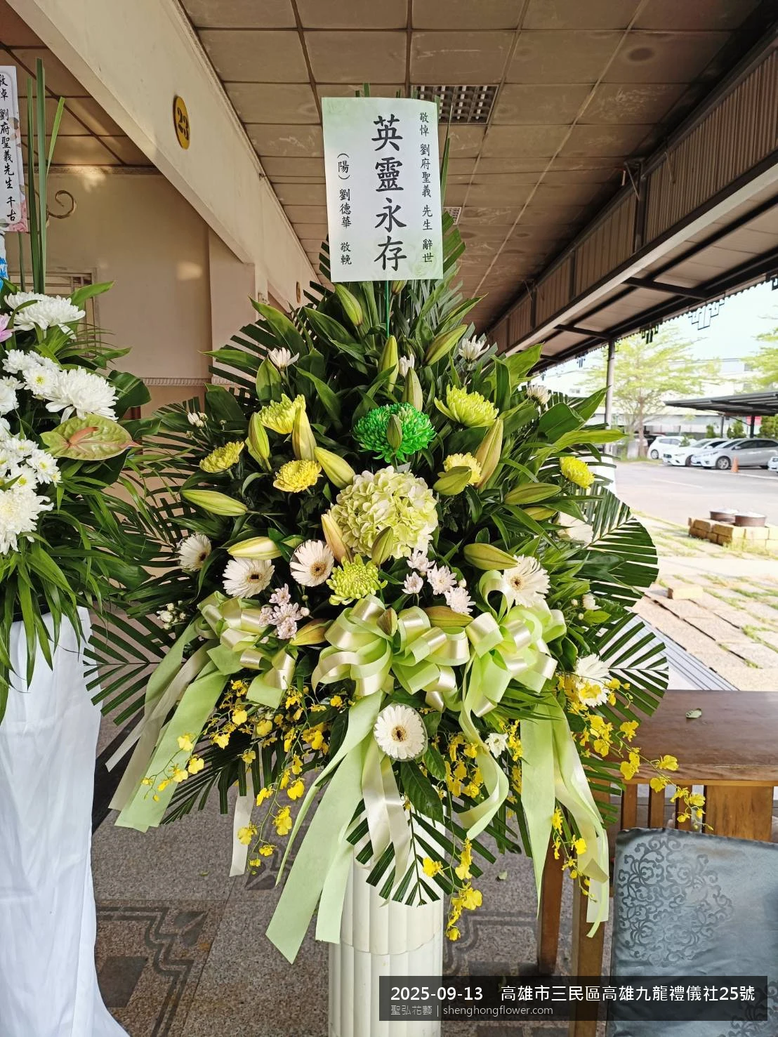 高雄三民高雄九龍禮儀社現場置高架白菊花籃，氛圍整潔有序。挑高花架穩固、字牌方向清晰，於初秋微涼氣候轉爽就位完成，配合主人家完成擺設，聖弘花藝在地團隊現場實拍照。