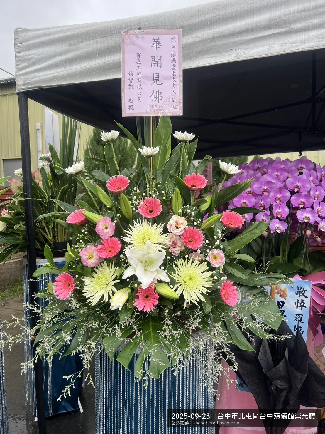 台中北屯台中殯儀館崇光廳前置高架白菊花籃，氛圍沉靜典雅。挑高花架穩固、字牌方向清晰，於初秋微涼氣候轉爽就位完成，陪伴家屬度過難捨時刻，聖弘花藝在地團隊現場實拍照。