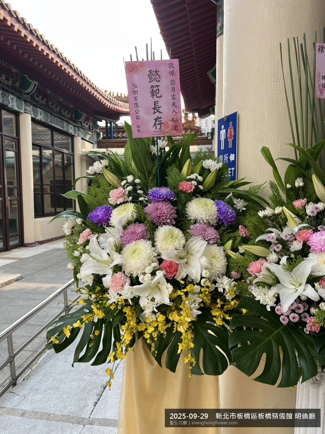 初秋微涼氣候轉爽下高架白菊花籃並陳，雙層花籃結構、上層紅玫瑰下層白菊，送達新北板橋板橋殯儀館 明倫廳前後整體陳設整齊，於現場完成定位，聖弘花藝在地團隊現場實拍照。