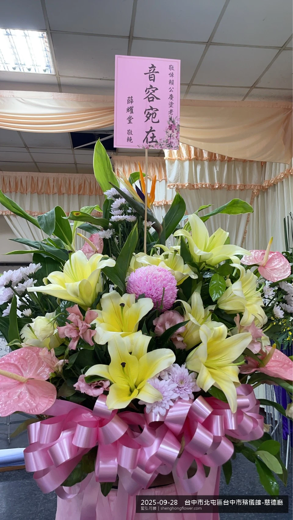 初秋微涼氣候轉爽下，台中北屯台中市殯儀館-慈德廳前光線柔和。我們選用高架白菊花籃，雙劍蘭挑高、黃菊鋪底，現場顯得素雅莊重，誠摯傳達對家屬的關懷，聖弘花藝在地團隊現場實拍照。
